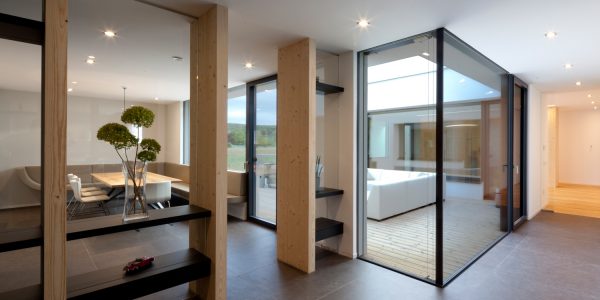 Ausblick in einen Innenhof mit großer Glasfront in einem Bungalow, der von Architekten geplant wurde