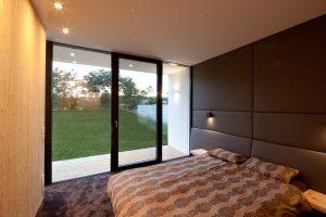 Bild eines Schlafzimmers mit Ausblick und großer Glasfront eines Bungalows, der von Architekten geplant wurde