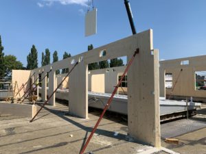 Innenansicht des Rohbaus bei dem Holzmassivwände gerade per Kran eingehoben, aufgestellt und eingerichtet werden